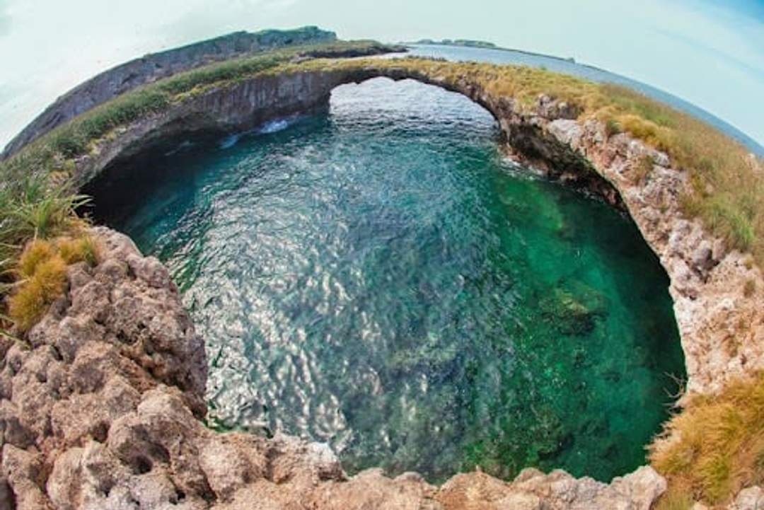 A natural rock formation arch over clear blue-green waters at Islas Marietas, a popular snorkeling spot near Puerto Vallarta, Mexico.