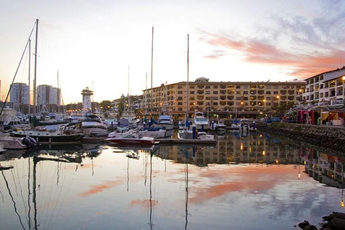 Vista al atardecer de Marina Vallarta en Puerto Vallarta con barcos y edificios frente al mar.