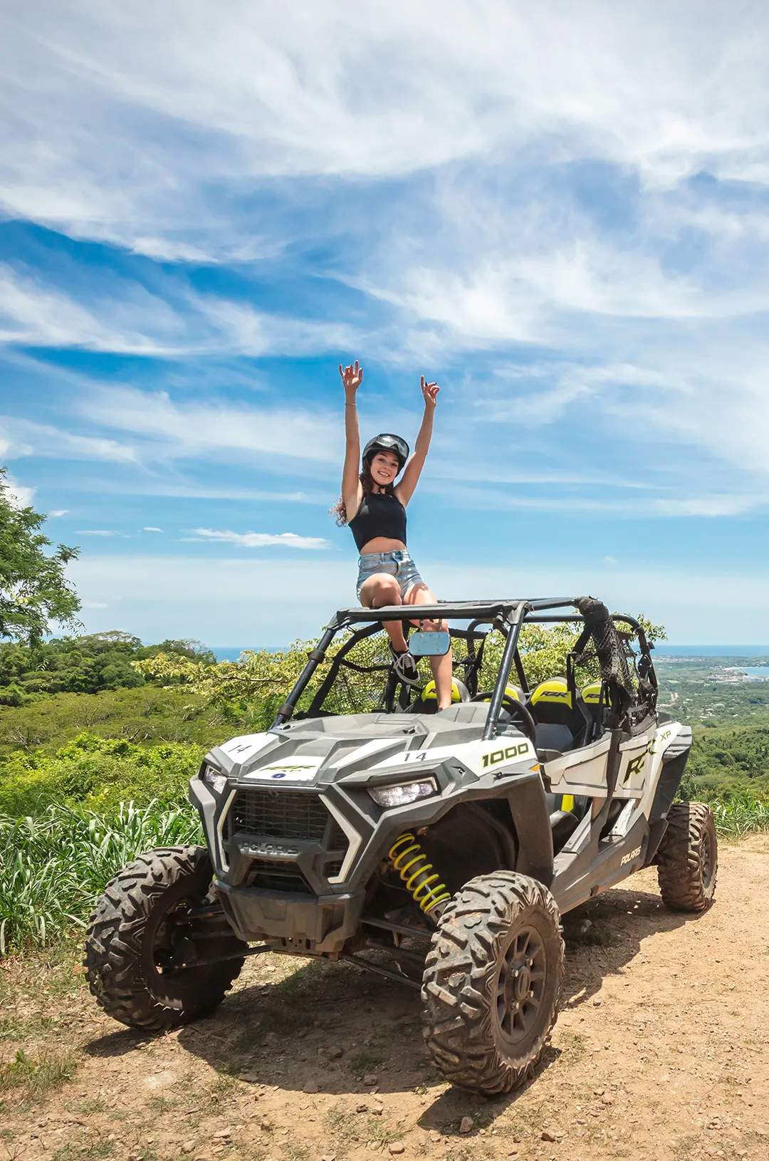 Woman on a Polaris RZR ATV tour at a scenic viewpoint overlooking the ocean near Sayulita, Mexico.