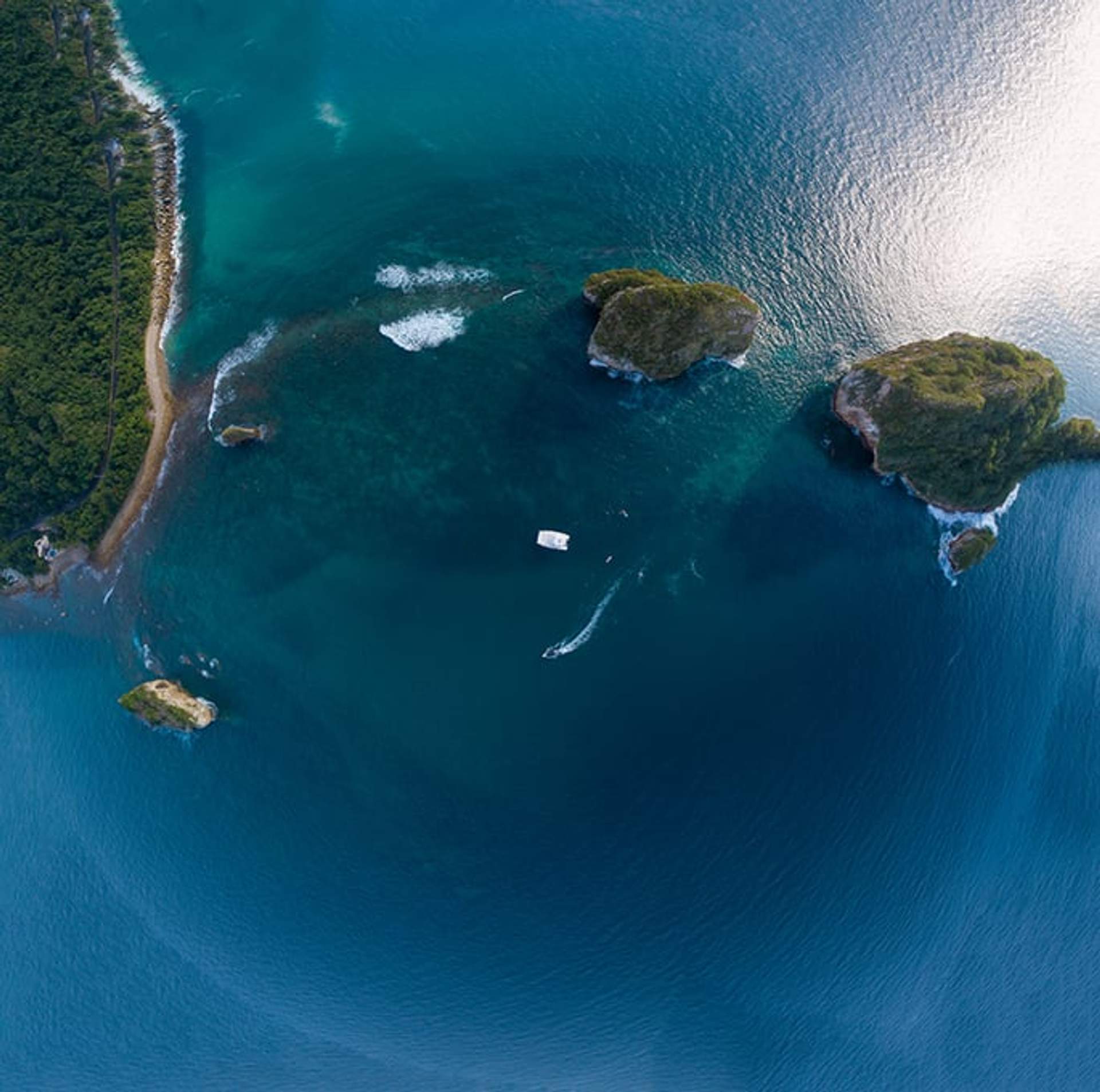 Vista aérea de Los Arcos en Puerto Vallarta, con pequeñas islas y un bote en las aguas turquesas.