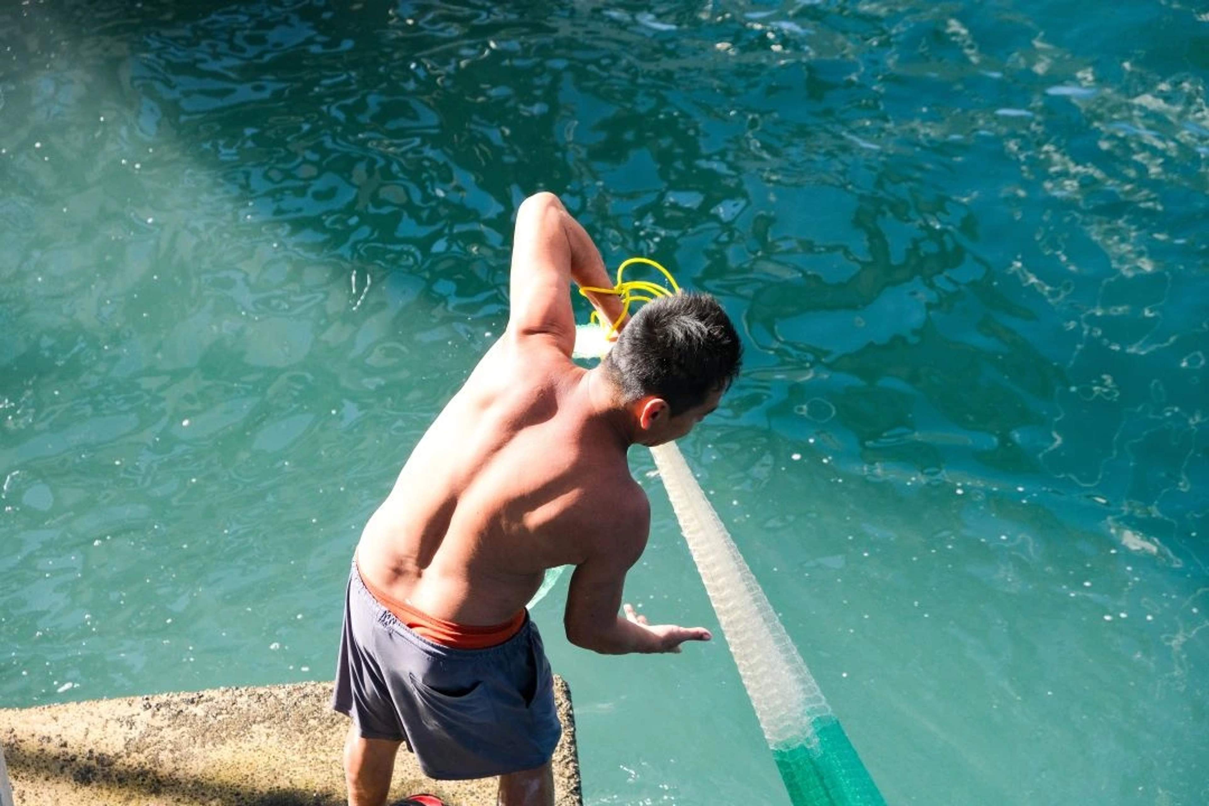 A man pulling in a fishing net at the edge of the water in Puerto Vallarta