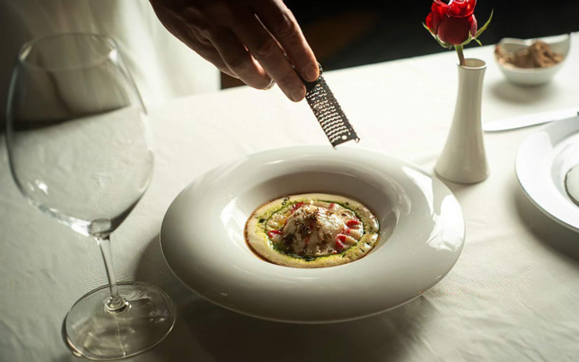 Un plato de risotto en un restaurante elegante, con una copa de vino.