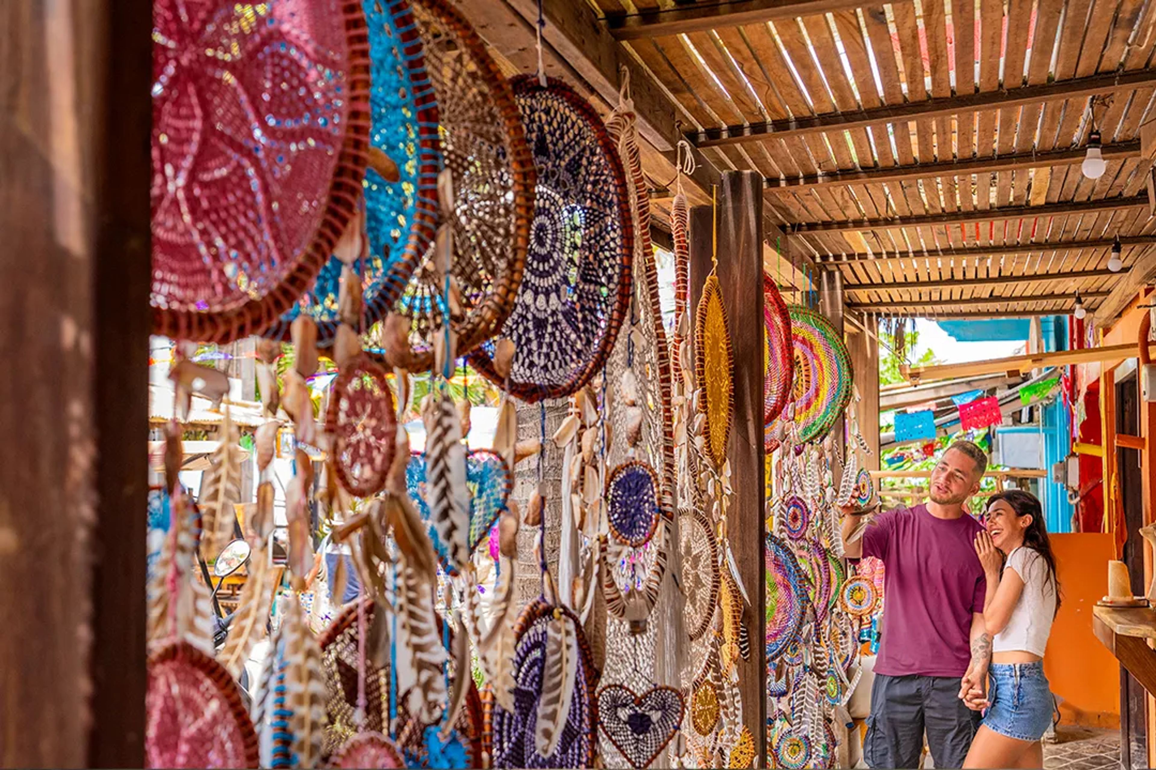 Una pareja agarrados de las manos en un pasillo lleno de atrapa sueños de todos los tamaños y colores diferentes