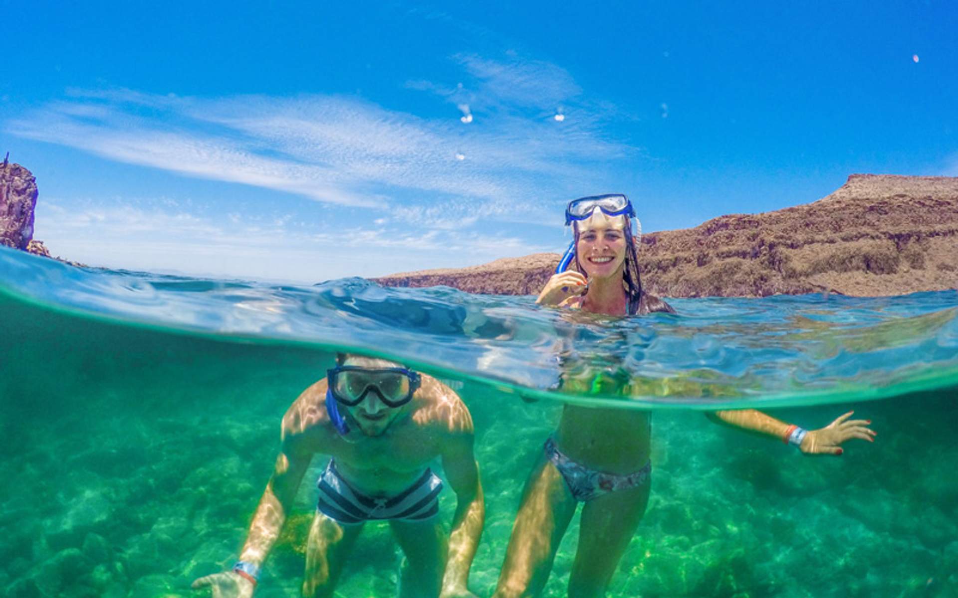 Couple snorkeling, split view with underwater and above water scene.