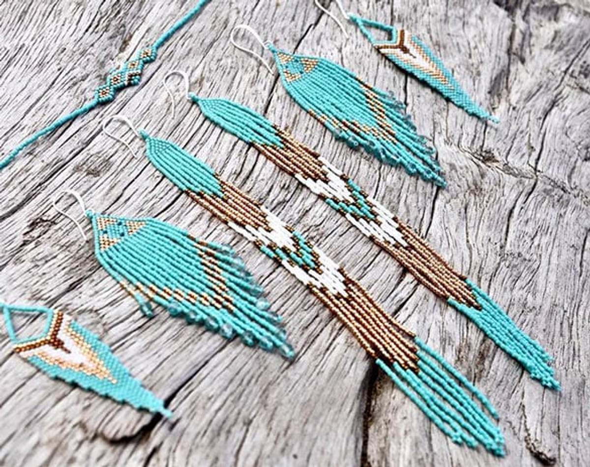 Aretes y collares hechos a mano con cuentas en turquesa y marrón sobre una superficie de madera rústica.