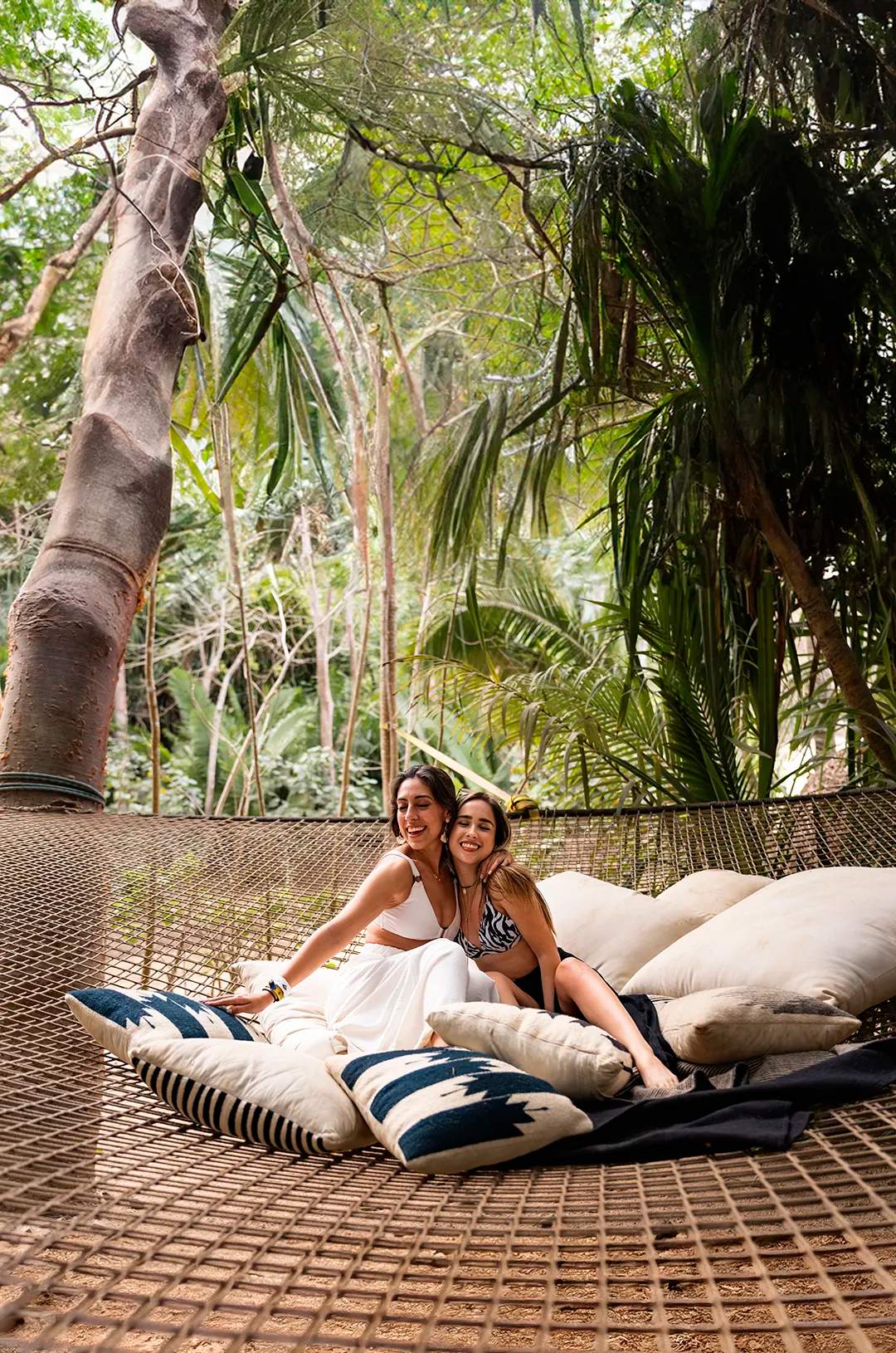 Friends having fun on a hanging net suspended from the palm trees at Majahuitas.