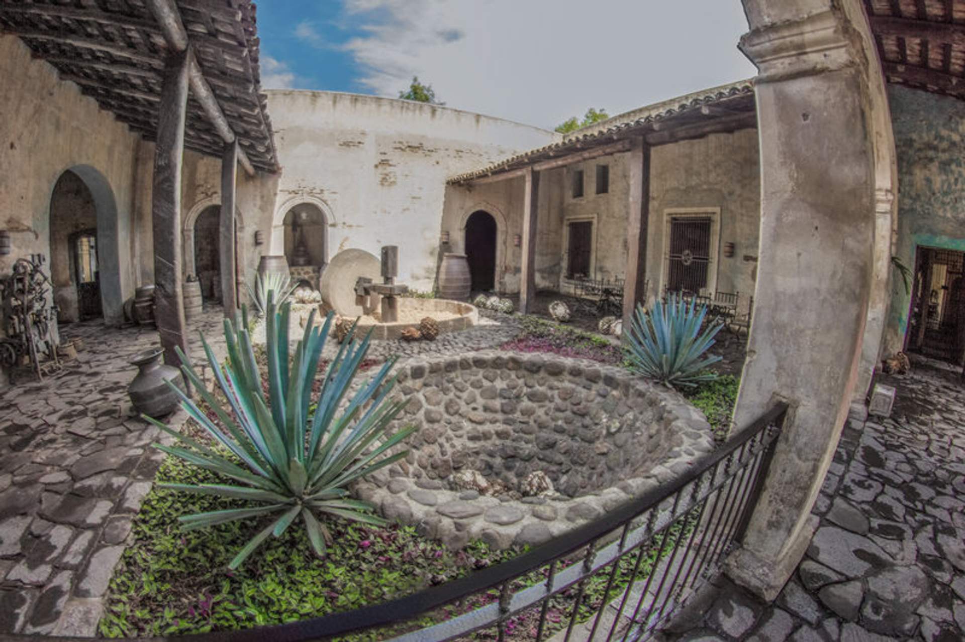 Vista del patio histórico de la Hacienda Jose Cuervo, con arquitectura de piedra y plantas de agave en Tequila, Jalisco.