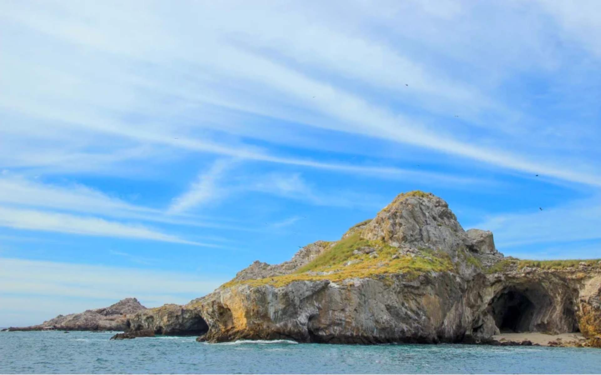 Paisaje costero rocoso con cuevas en las Islas Marietas en Nayarit, México, bajo un cielo azul claro.