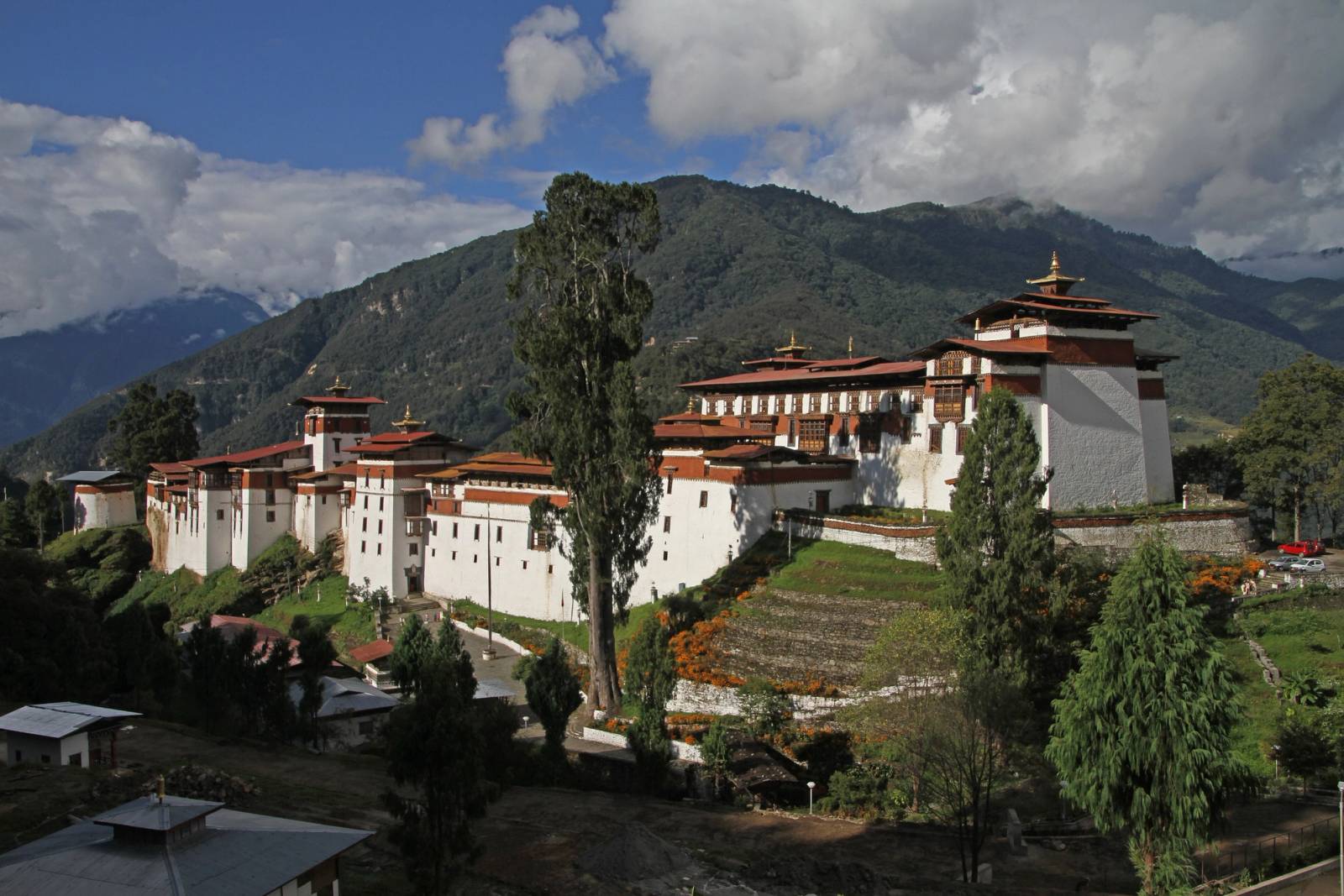 Trongsa Dzong's white walls and red roofs spread along a ridge below forested mountains