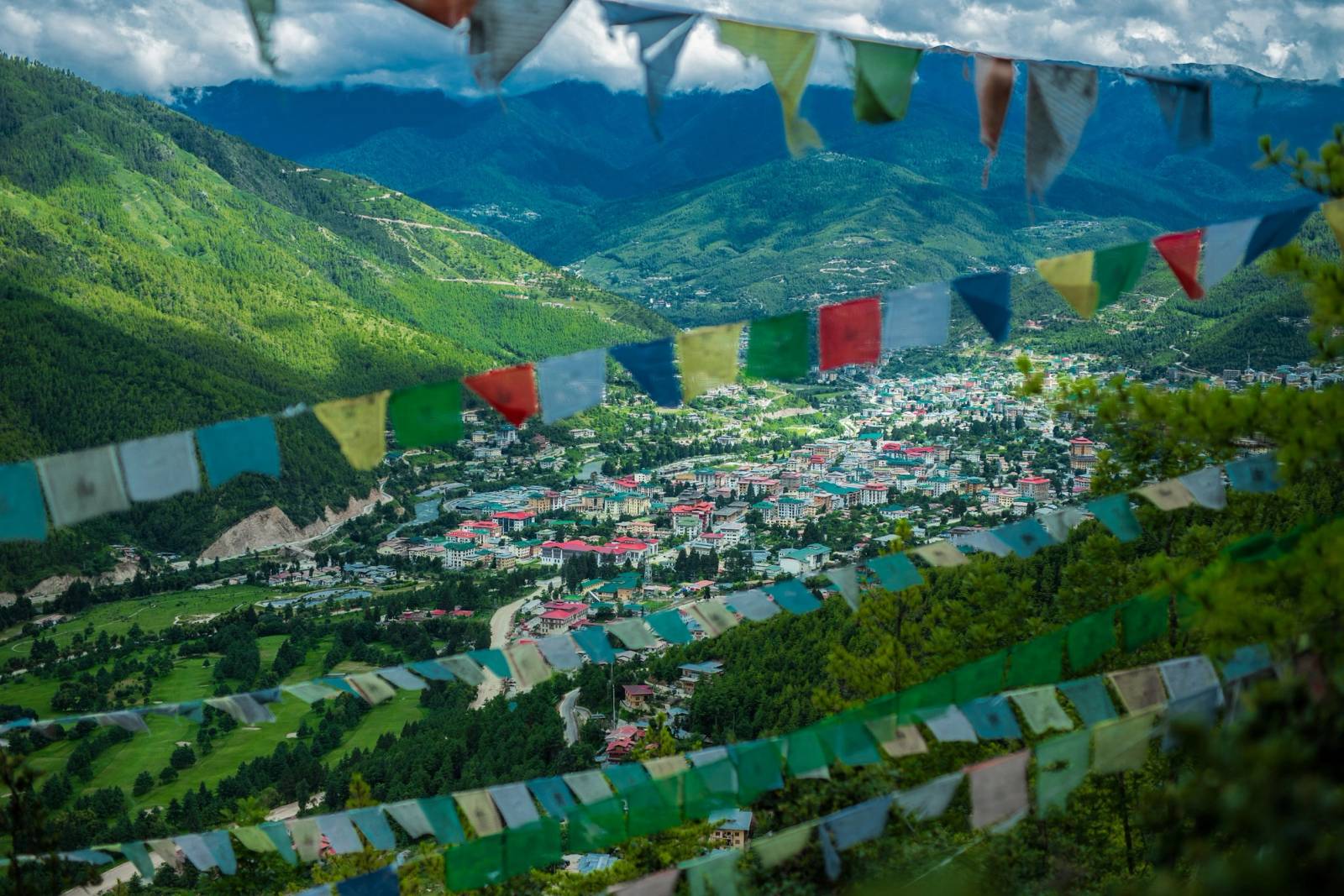 Prayer flags strung above a green valley dotted with houses