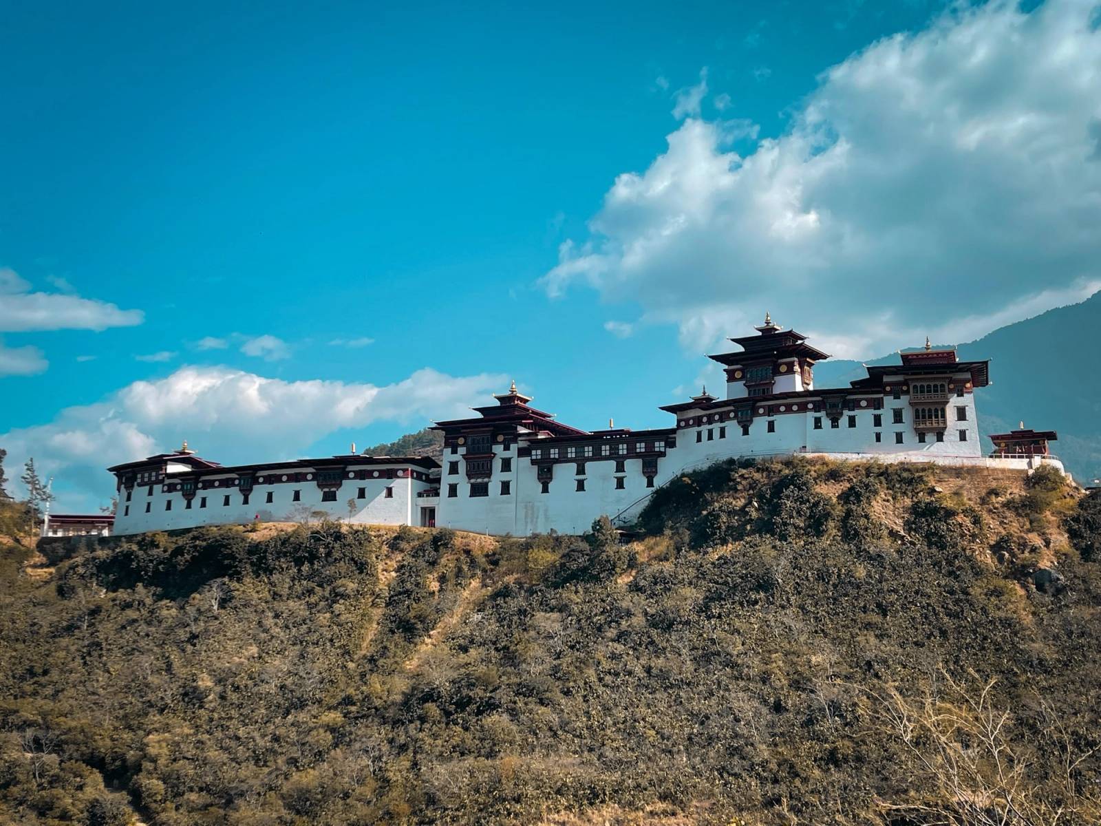 The rebuilt Wangdue Phodrang Dzong stretched along a dry ridgetop under a blue sky