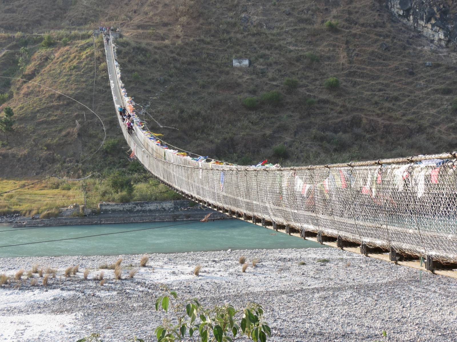 The Punakha suspension bridge, hung with prayer flags, crossing the Pho Chhu to the far bank