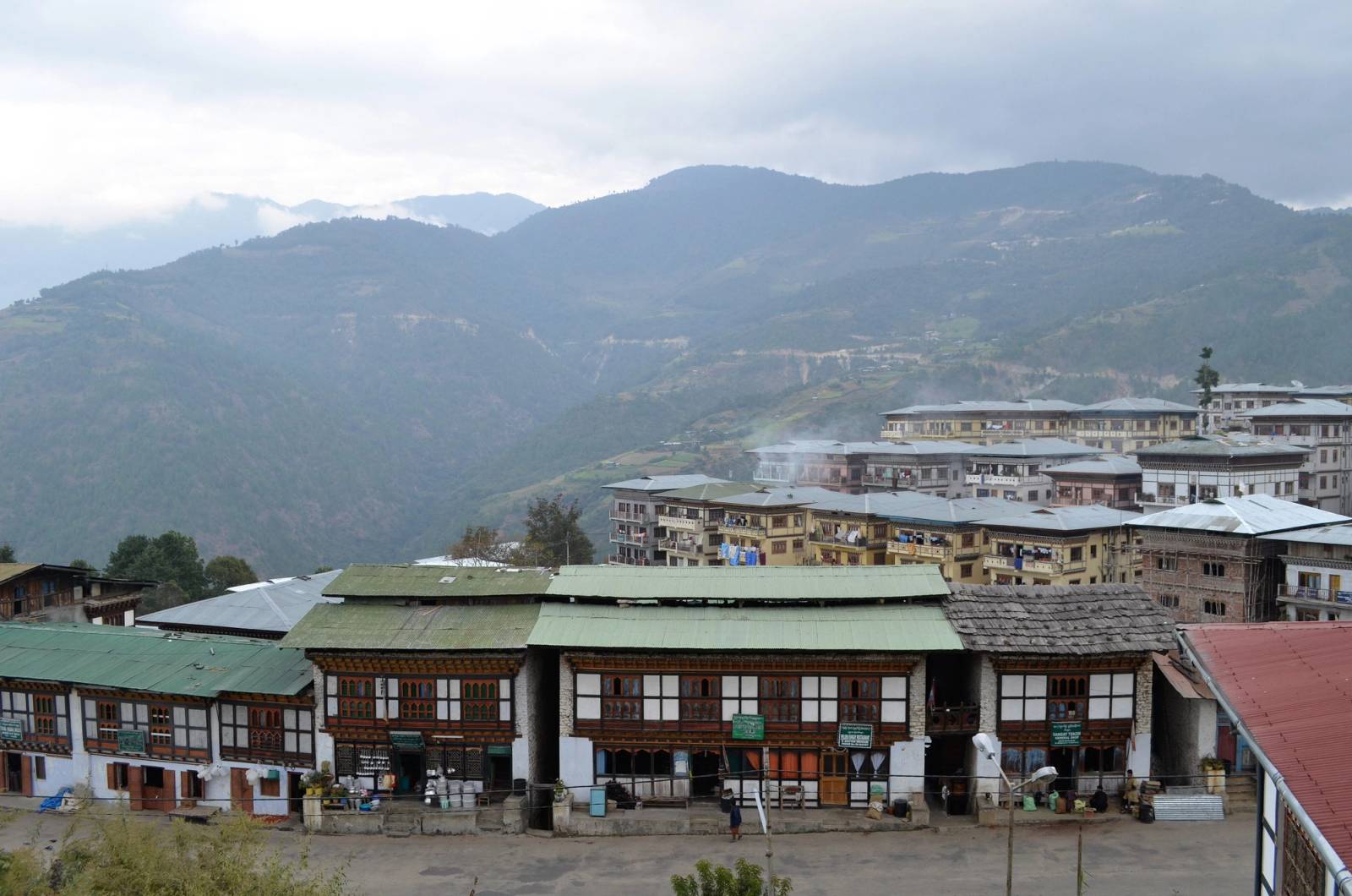 Mongar town's rows of traditional shopfronts on a ridge, with hazy hills behind