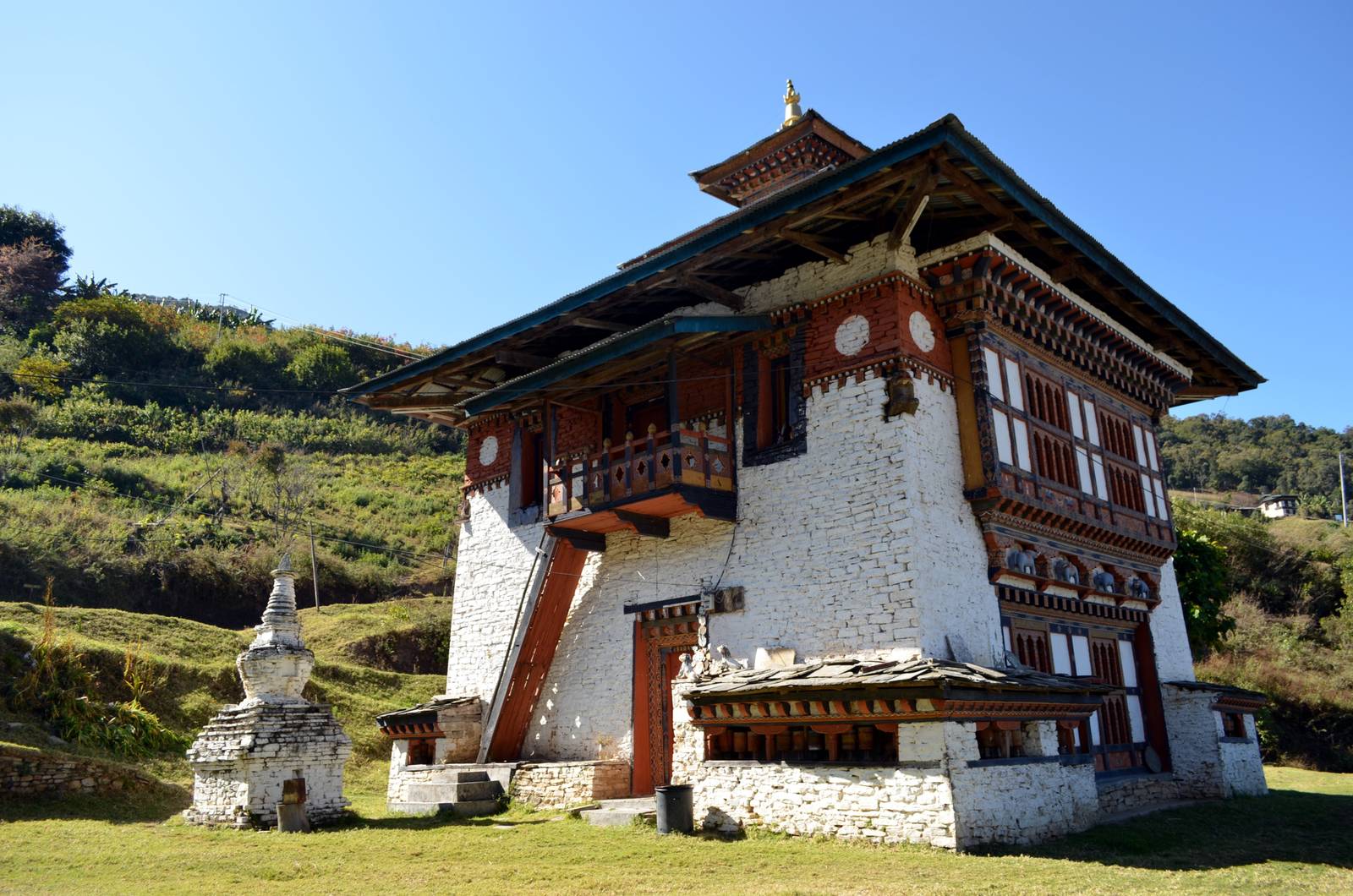Yakgang Lhakhang, a whitewashed temple with a small chorten beside it on a grassy slope near Mongar