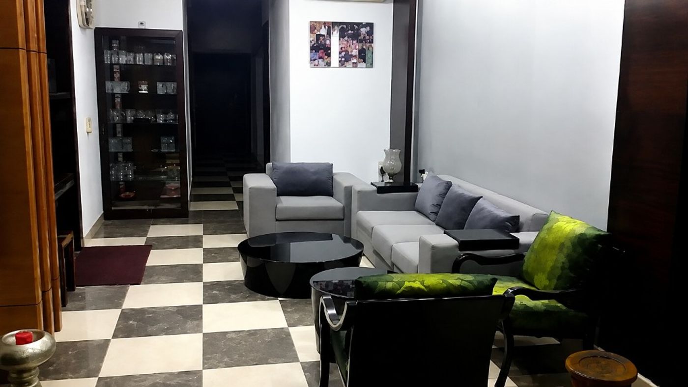 Mr. Shekhar Agarwal living room with grey sofa, green leaf-pattern chairs, black tables, and checkered marble floor