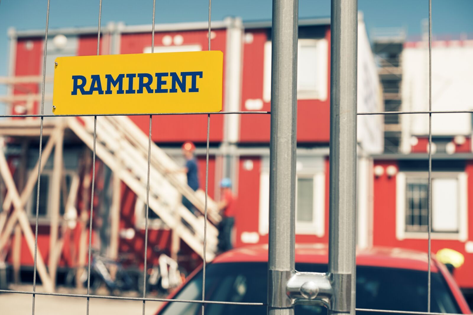 Skylt med texten "Ramirent" som sitter på ett staket vid en byggarbetsplats