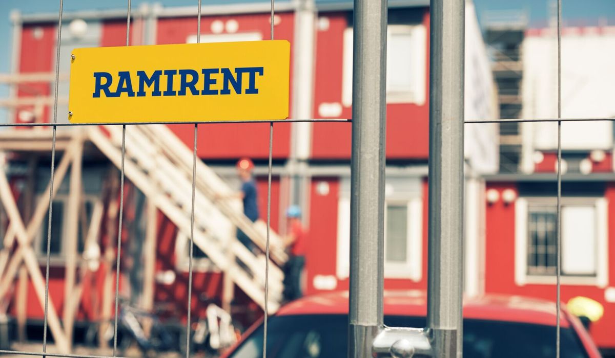 Skylt med texten "Ramirent" som sitter på ett staket vid en byggarbetsplats