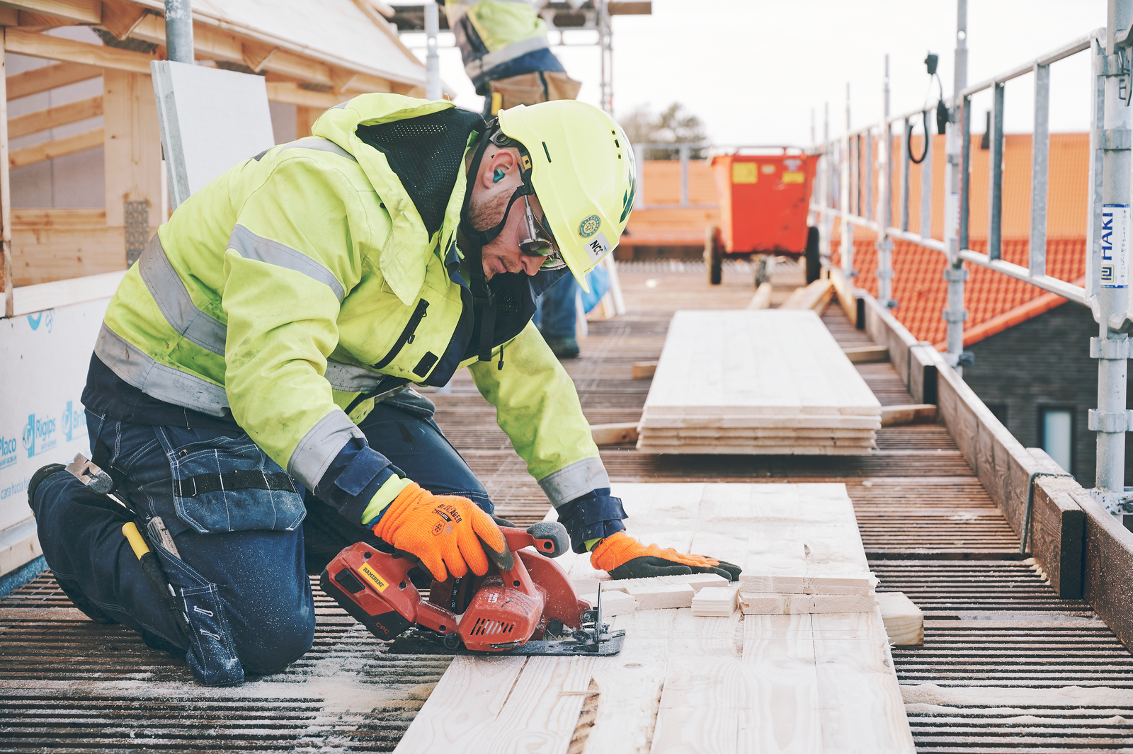 Byggarbetare i skyddsutrustning använder en cirkelsåg på bygget. Bli kund hos Ramirent för att hyra maskiner och verktyg.
