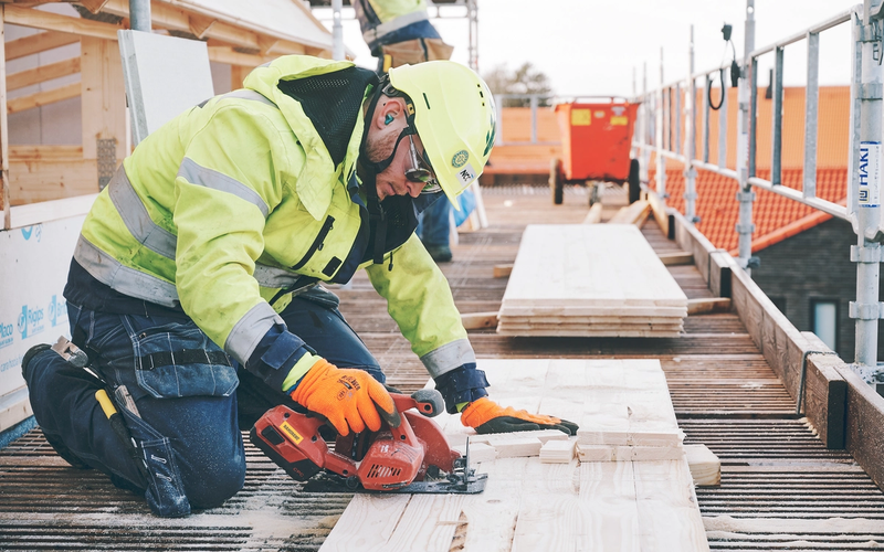 Byggarbetare i skyddsutrustning använder en cirkelsåg på bygget. Bli kund hos Ramirent för att hyra maskiner och verktyg.