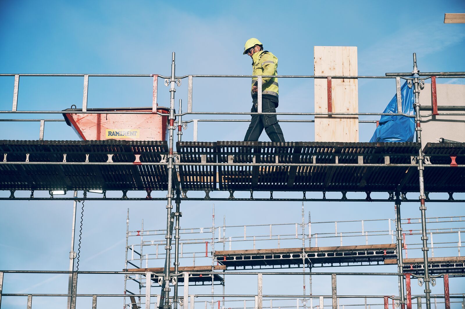 En yrkesarbetare på en byggställning som symboliserar Ramirents arbete för en hållbar byggbransch genom säkerhet, cirkulära lösningar och effektiv resursanvändning.
