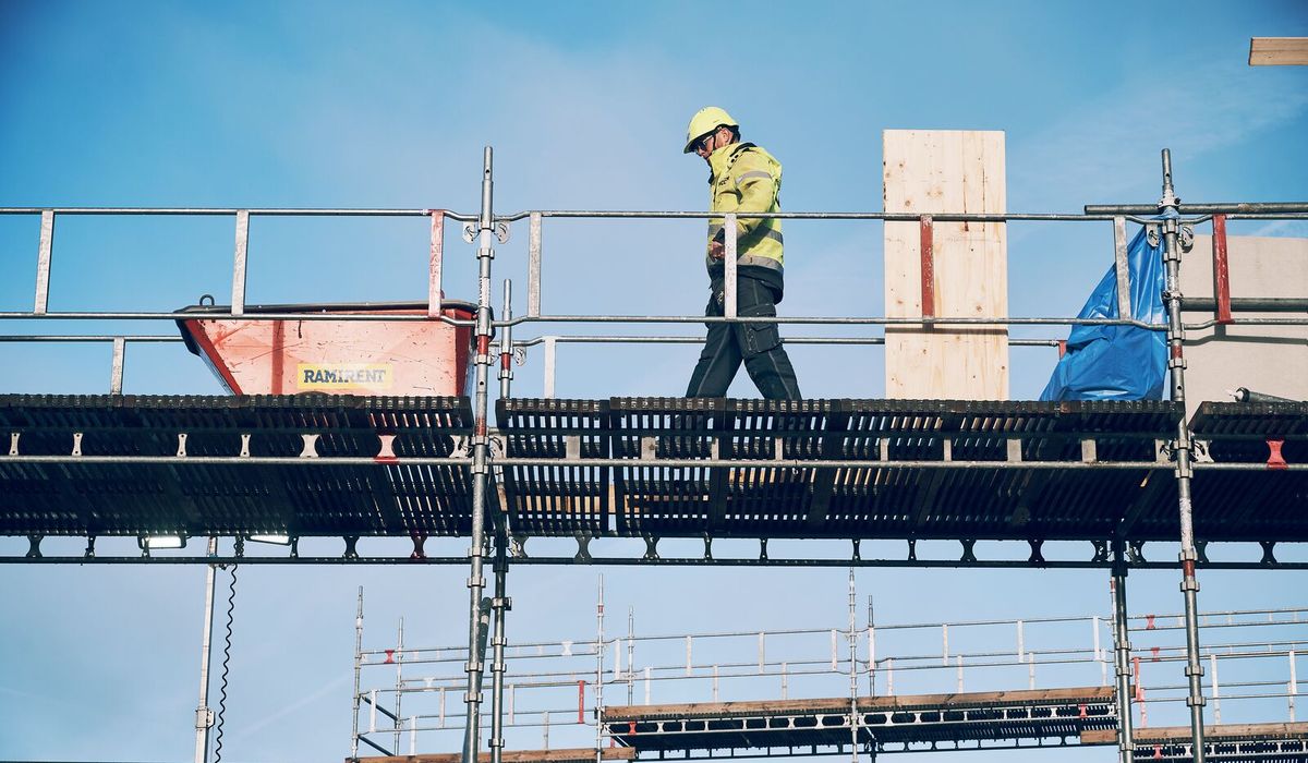 En yrkesarbetare på en byggställning som symboliserar Ramirents arbete för en hållbar byggbransch genom säkerhet, cirkulära lösningar och effektiv resursanvändning.