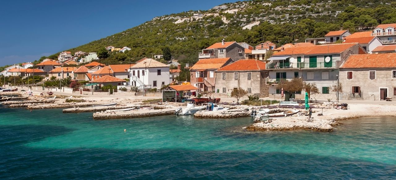 Turquoise sea water with residential houses on shore in the bay of Kaprije, Croatia