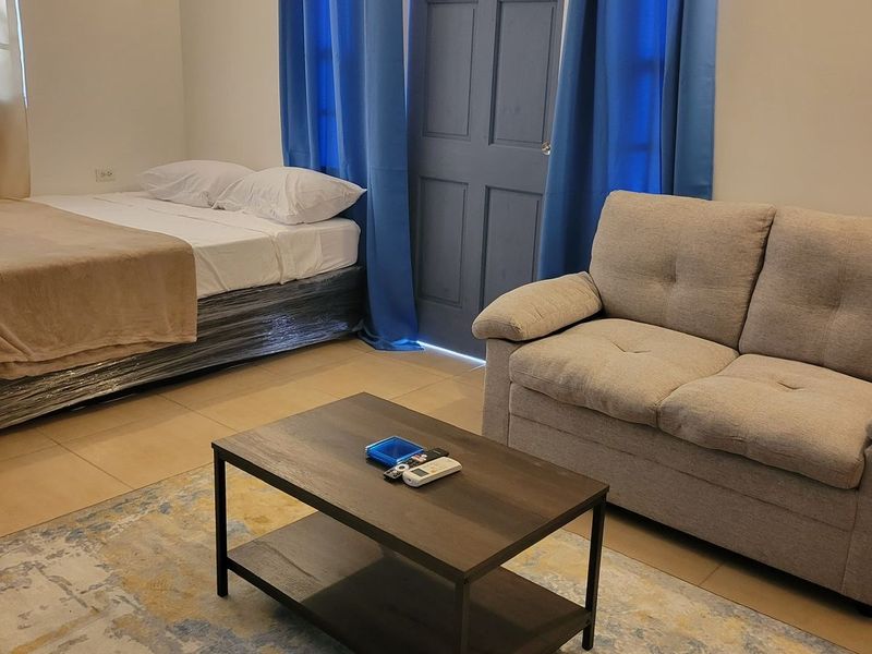 Room with a double bed, two-seat sofa and blue curtains