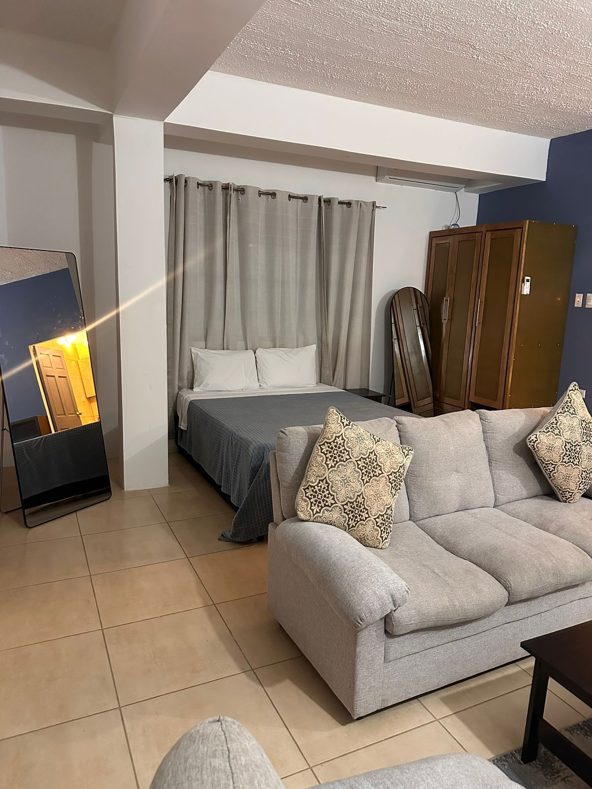 Room with a double bed, sofa, wardrobe and full-length mirror