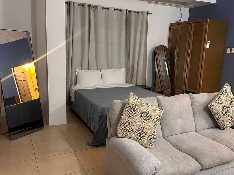 Room with a double bed, sofa, wardrobe and full-length mirror