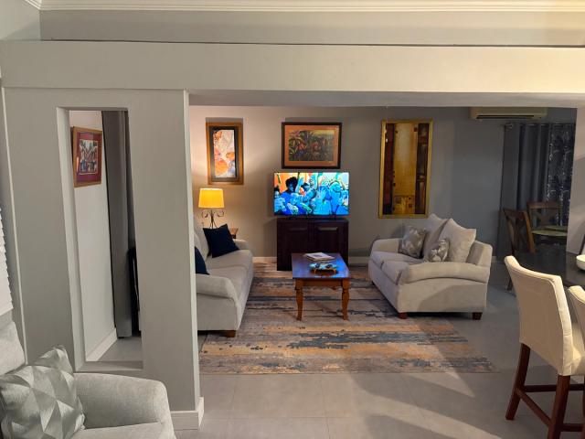 Living and dining area with two sofas, framed artwork and a ceiling fan