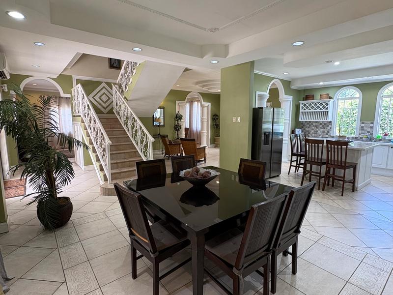 Open-plan dining area featuring a dark wooden dining table, decorative staircase and direct access to the fully equipped kitchen.