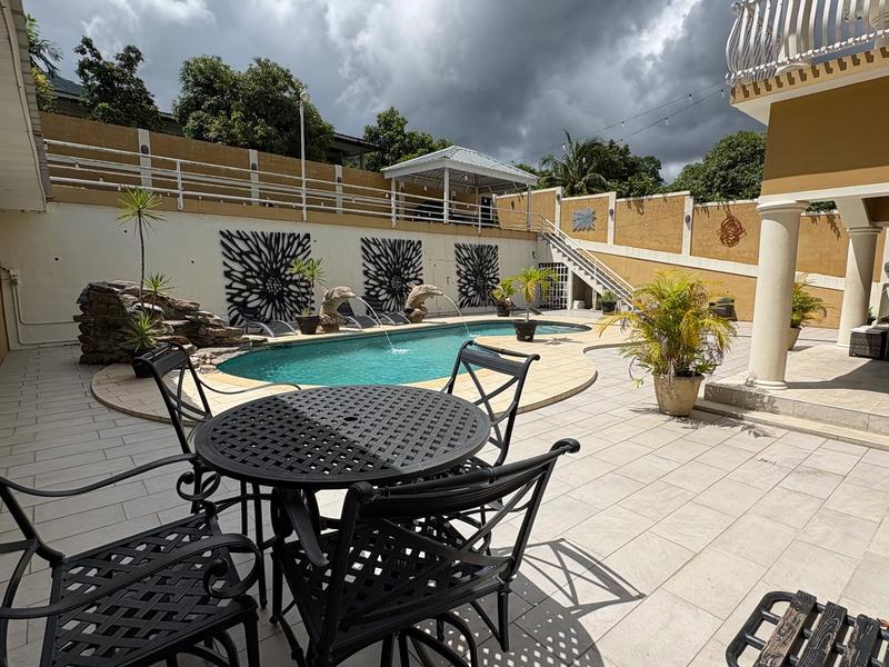 Outdoor pool area featuring a swimming pool, patio dining furniture, lounge chairs and a spacious courtyard surrounded by the villa’s exterior.