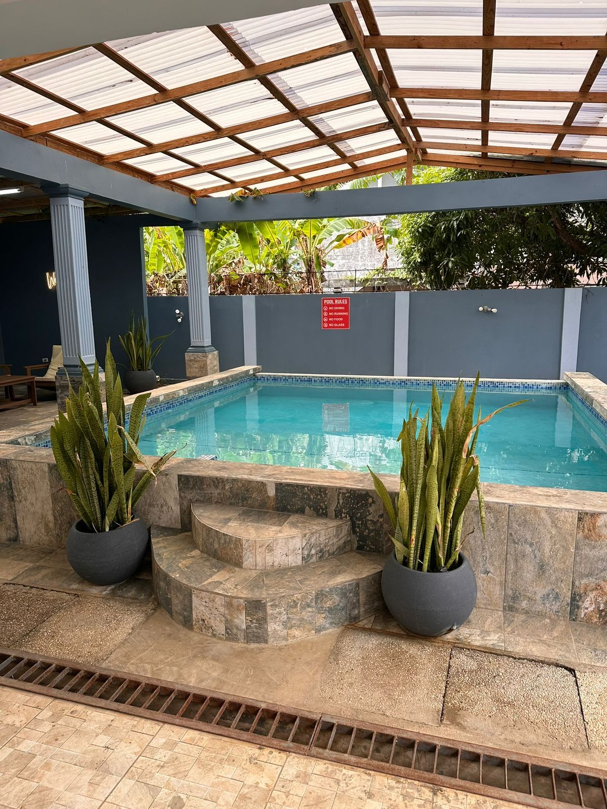 Covered pool with a stone patio and potted plants at 11 Havilah Drive