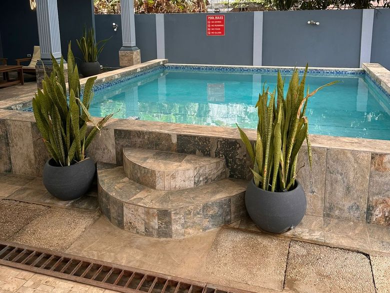 Covered pool with a stone patio and potted plants at 11 Havilah Drive