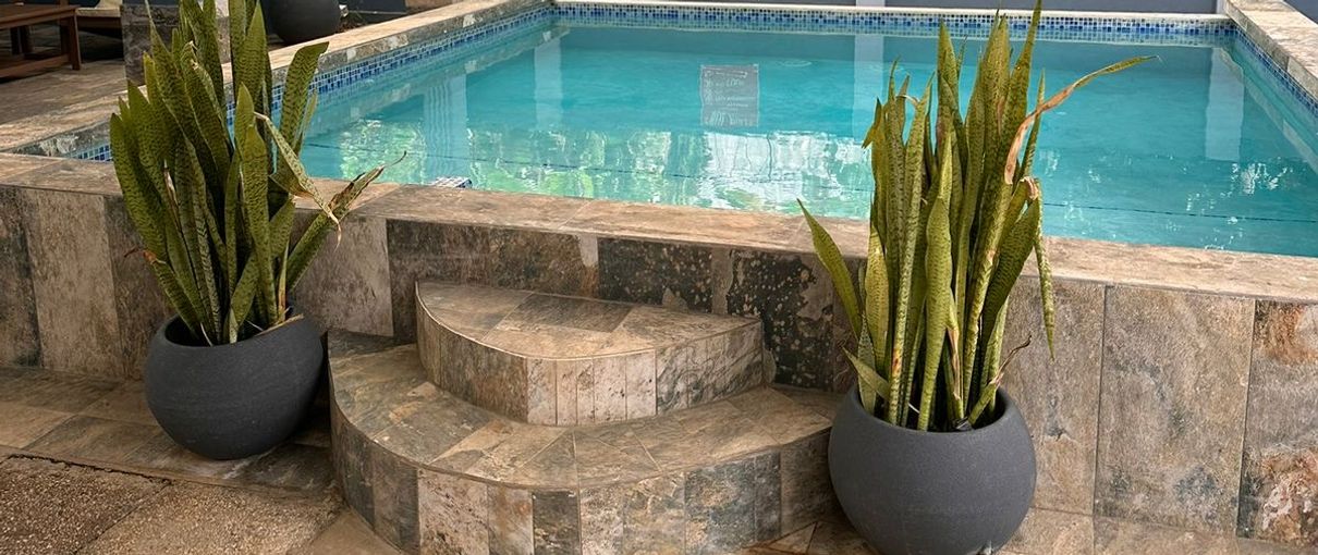 Covered pool with a stone patio and potted plants at 11 Havilah Drive