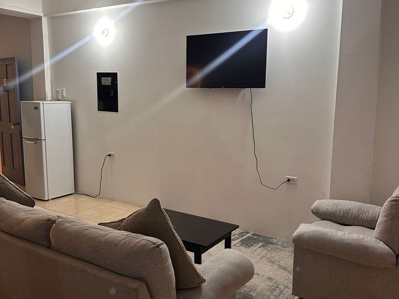Lounge with sofas, a wall-mounted television and a fridge