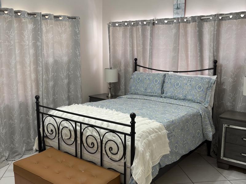 Comfortable bedroom featuring a queen sized bed with a decorative metal frame, bedside tables, air conditioning and a ceiling fan.