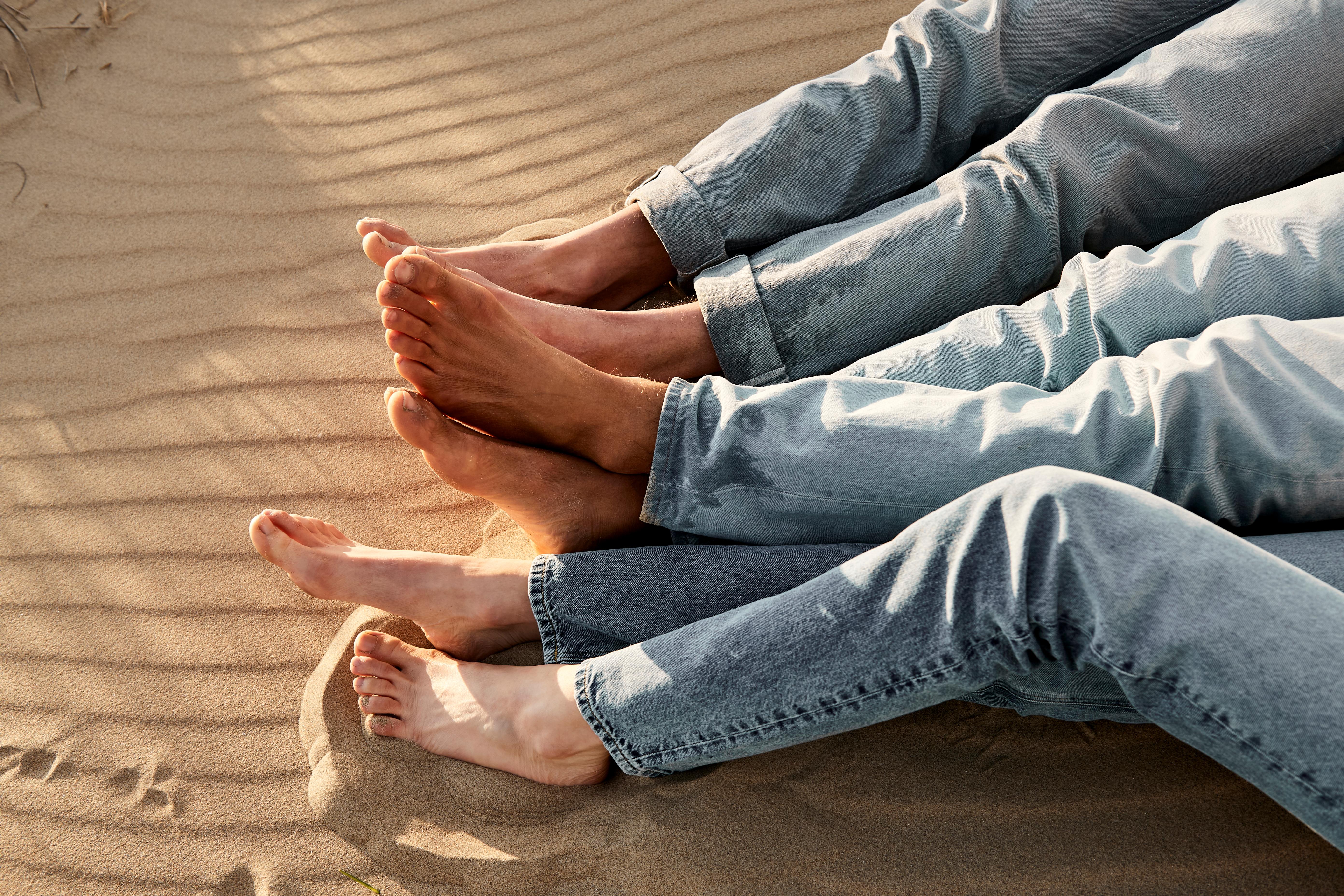 Menschen in Jeans sitzen im Sandstrand.