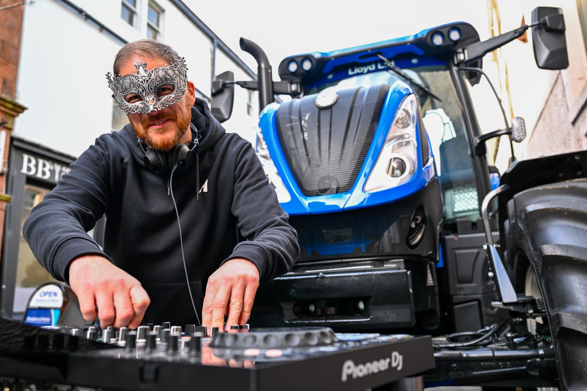 A DJ performing in front of a tractor