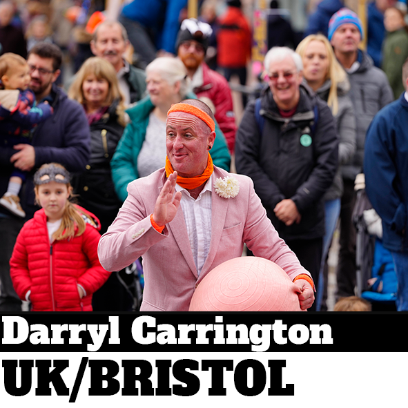 Street performer in pink suit holding ball