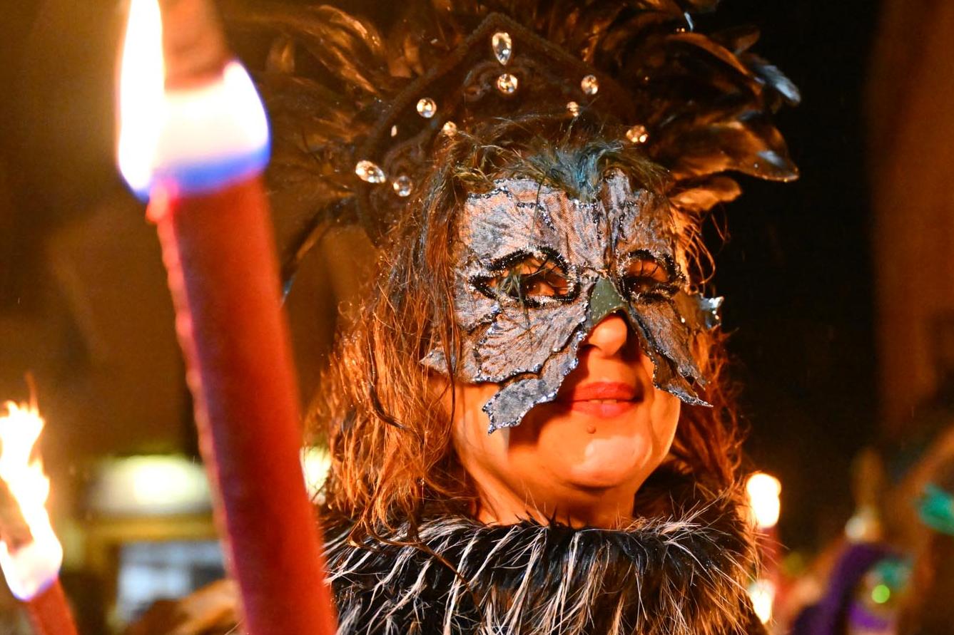 A masked woman with a torch