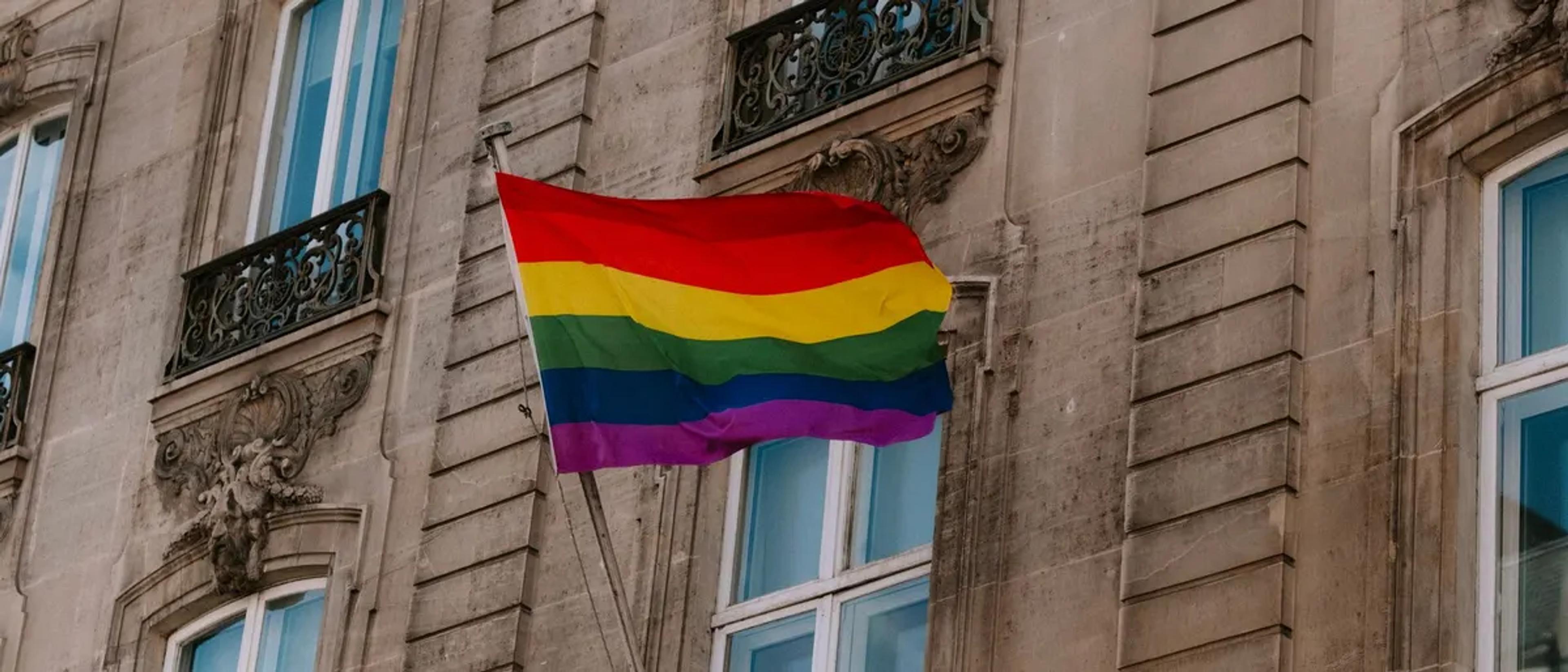 Rainbow Pride flag flying from the balcony of a historic European building