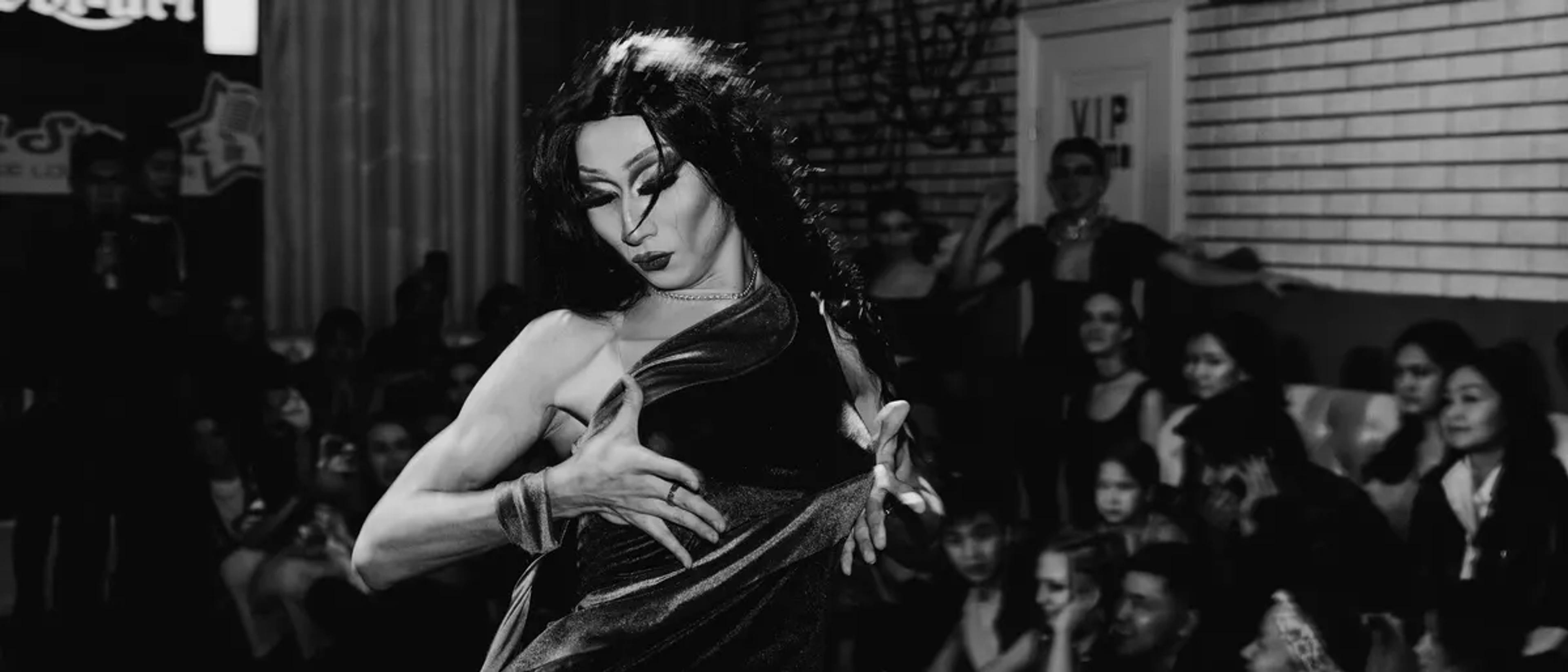Black and white photo of a drag performer on stage in a nightclub