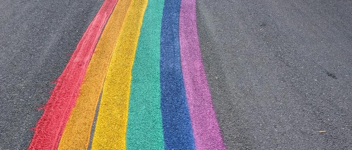 A rainbow-painted Pride crosswalk running across a city street