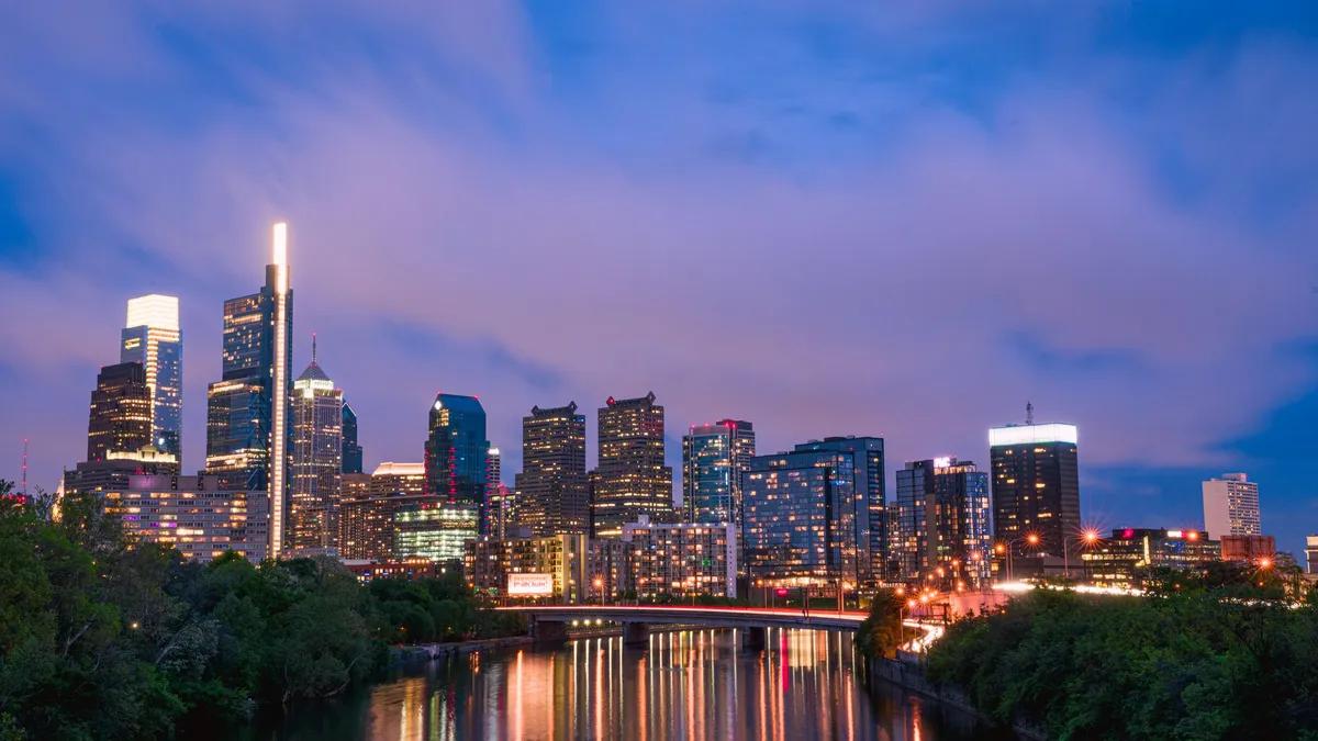 The Philadelphia skyline lit at dusk, reflected in the Schuylkill River