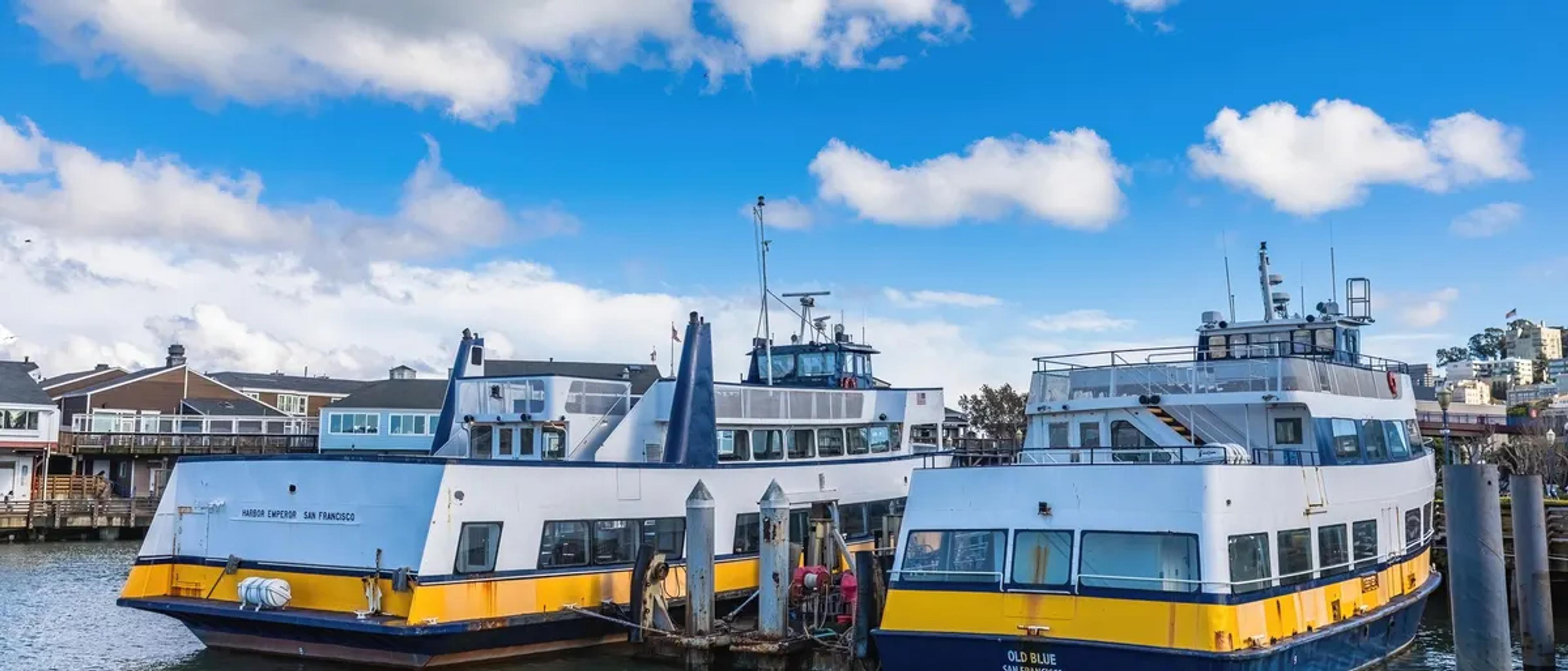 Passenger ferries docked at a harbor pier under a blue sky