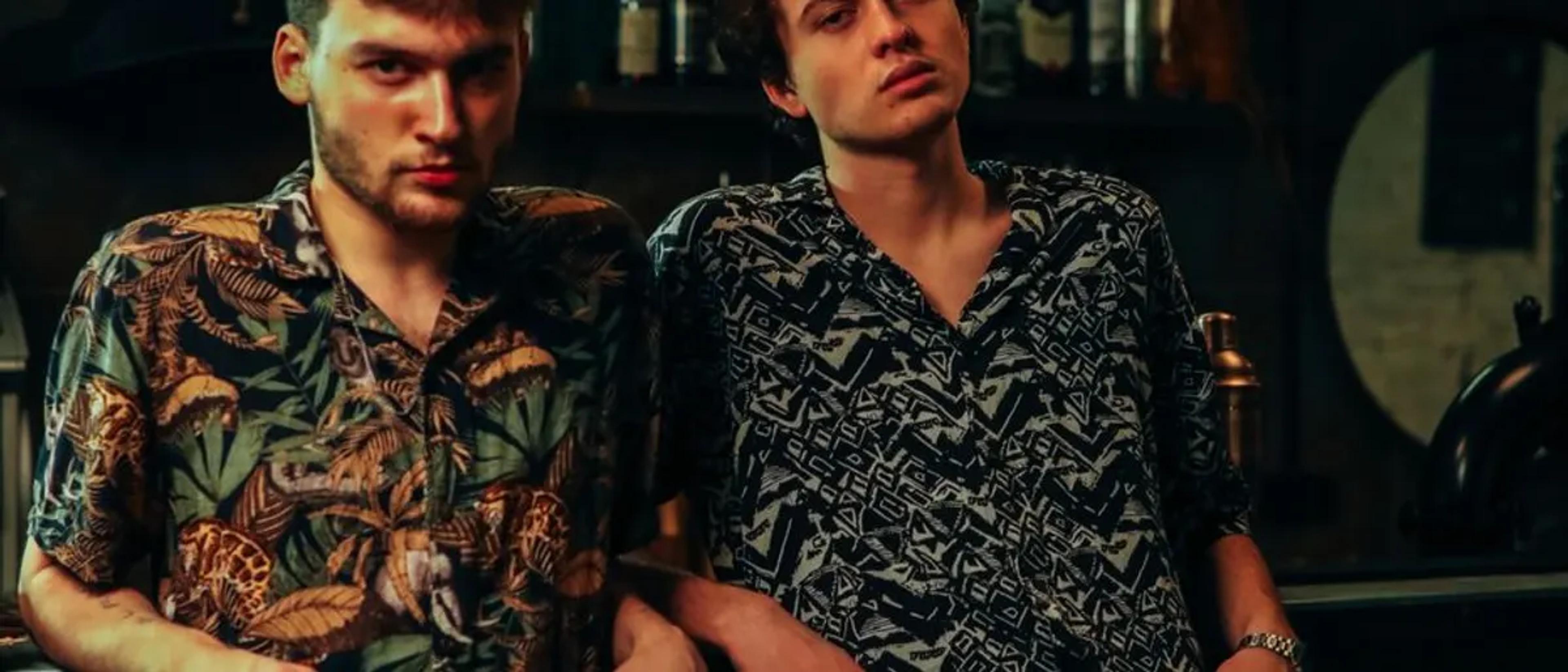 Two men sitting together at a dimly lit bar counter