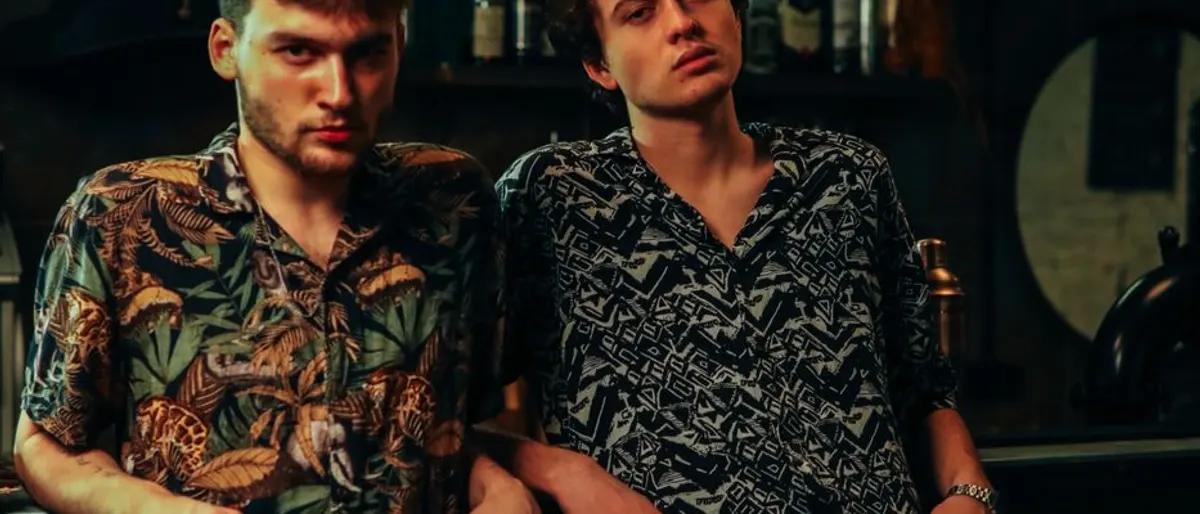 Two men sitting together at a dimly lit bar counter