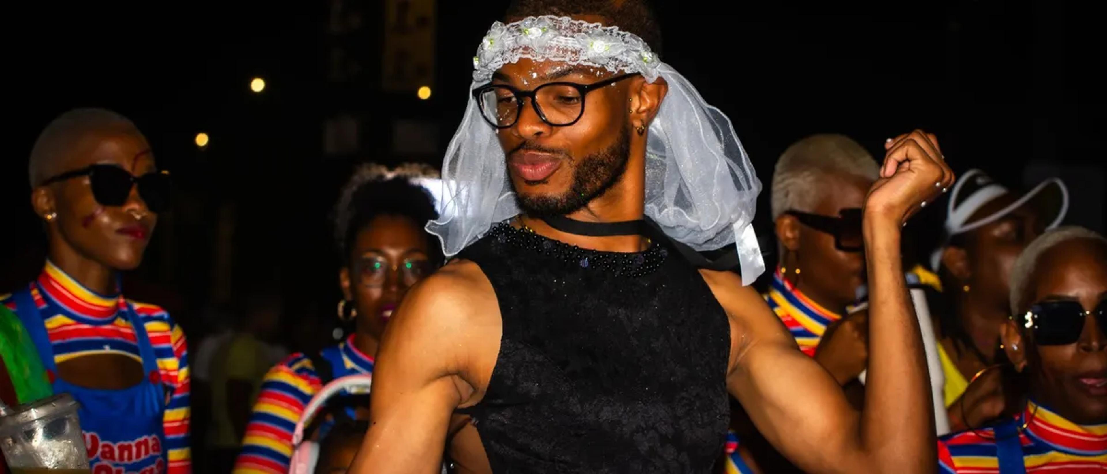 A joyful group of Black friends celebrating together at a Pride event with rainbow accents