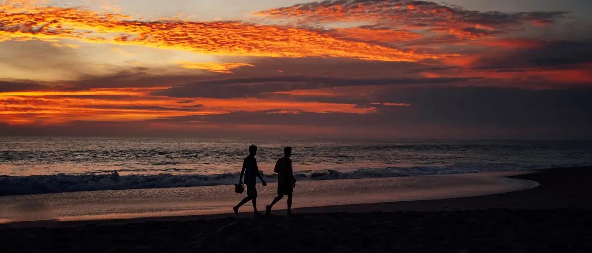 Two men walking along the beach at sunset on the Oaxaca coast of Mexico